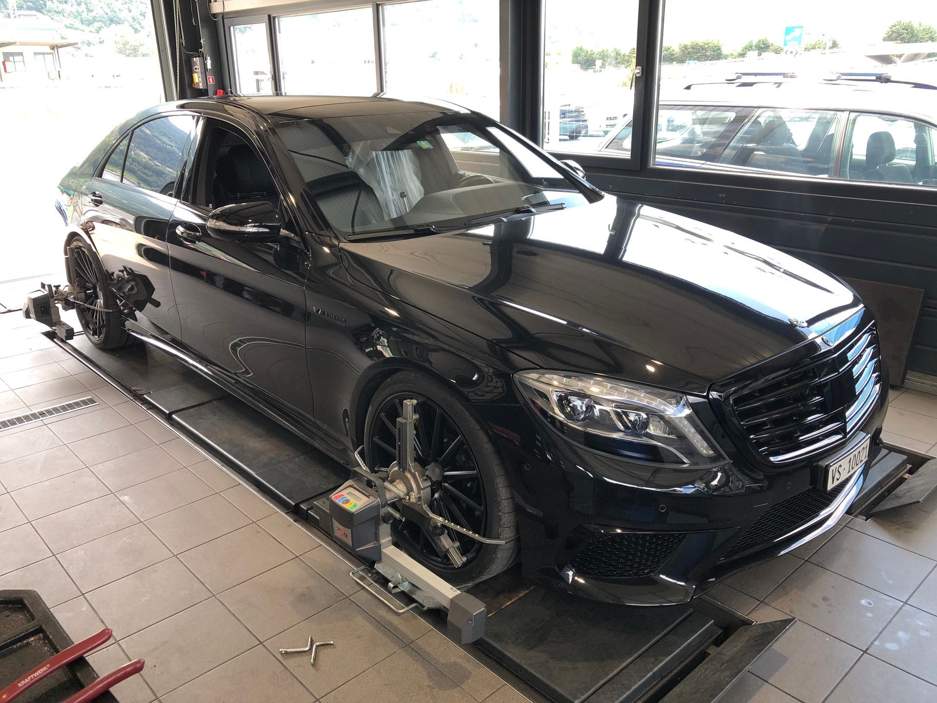 Une Mercedes Benz noire est assise sur un ascenseur dans un garage.