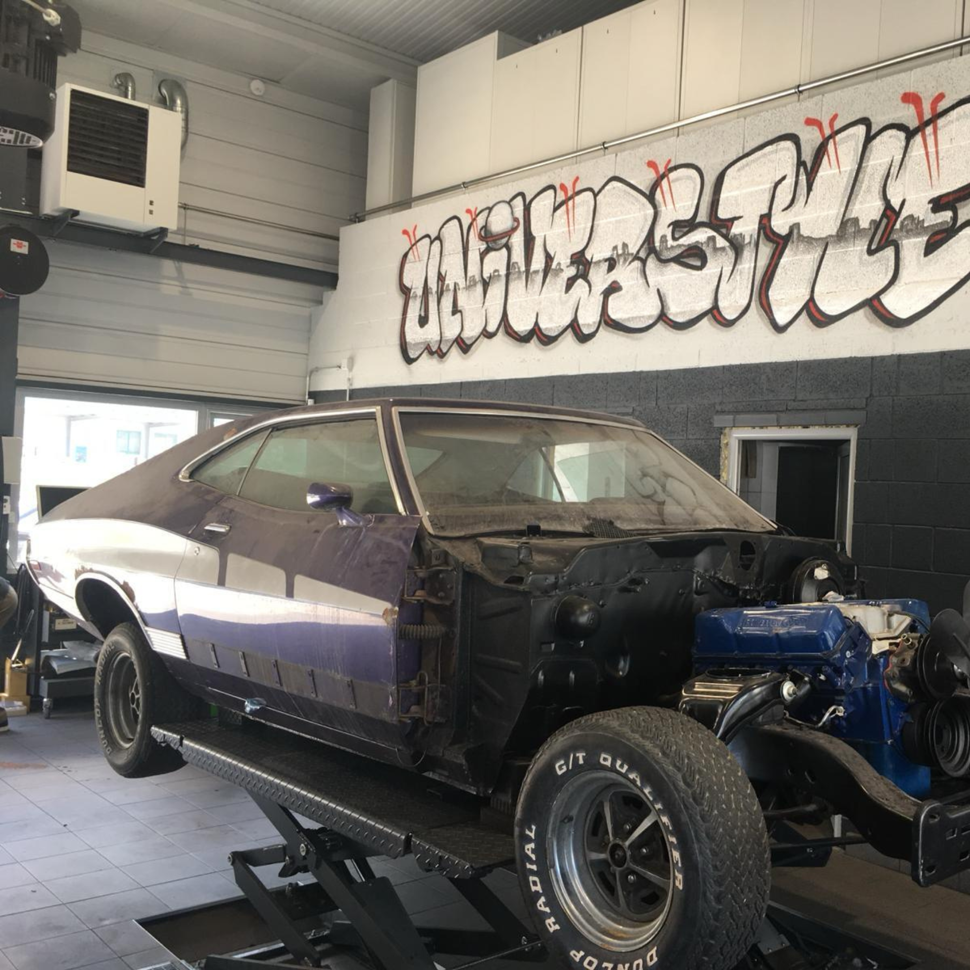 Une voiture violette est assise sur un ascenseur dans un garage