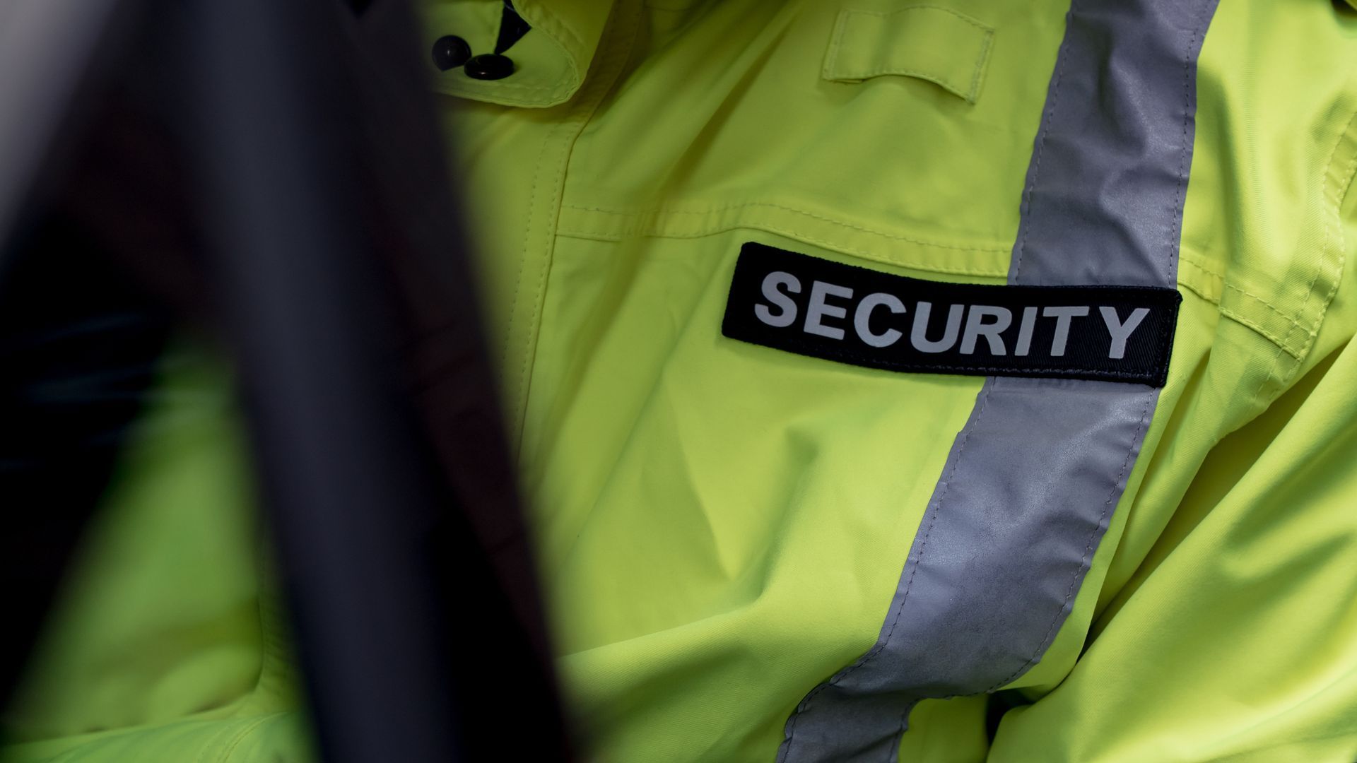 Security guard wearing a neon yellow jacket with a 