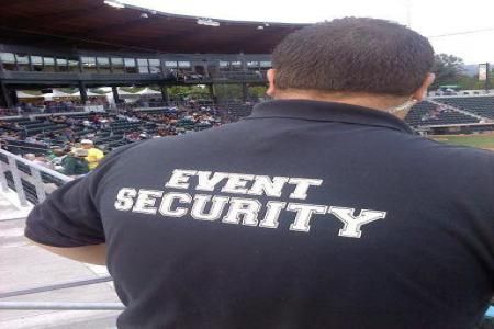 Security guard in blue uniform with arms crossed.