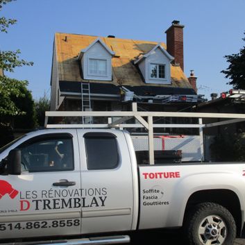 Camion argenté avec logo « Les Rénovations D'Tremblay »; travaux de toiture en cours sur une maison à deux étages.