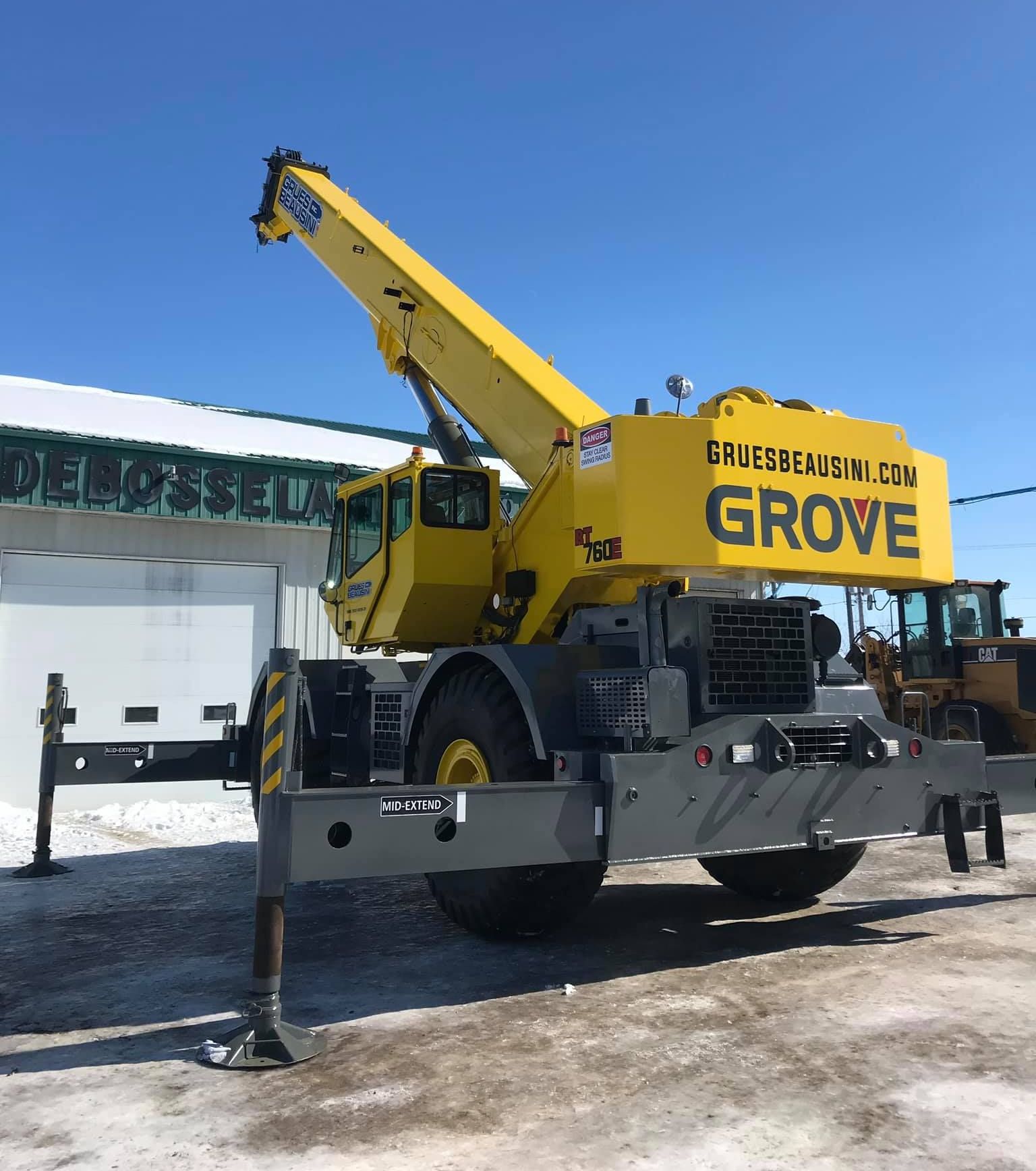 Une grue jaune est garée devant un bâtiment