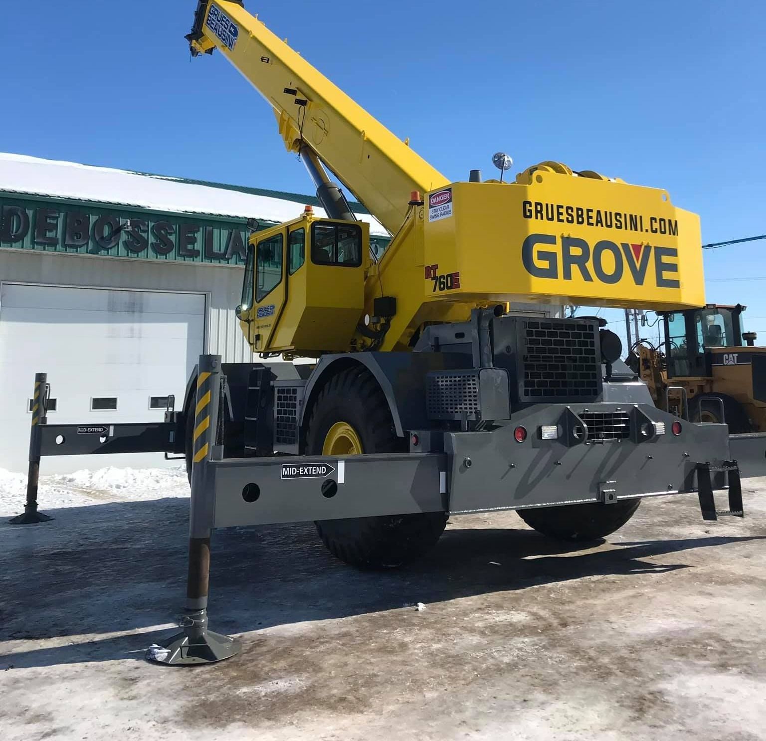 Grue Yellow Grove sur châssis gris, installée sur des stabilisateurs dans une zone enneigée.