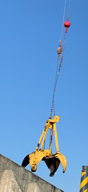 Une griffe jaune est suspendue à une grue contre un ciel bleu