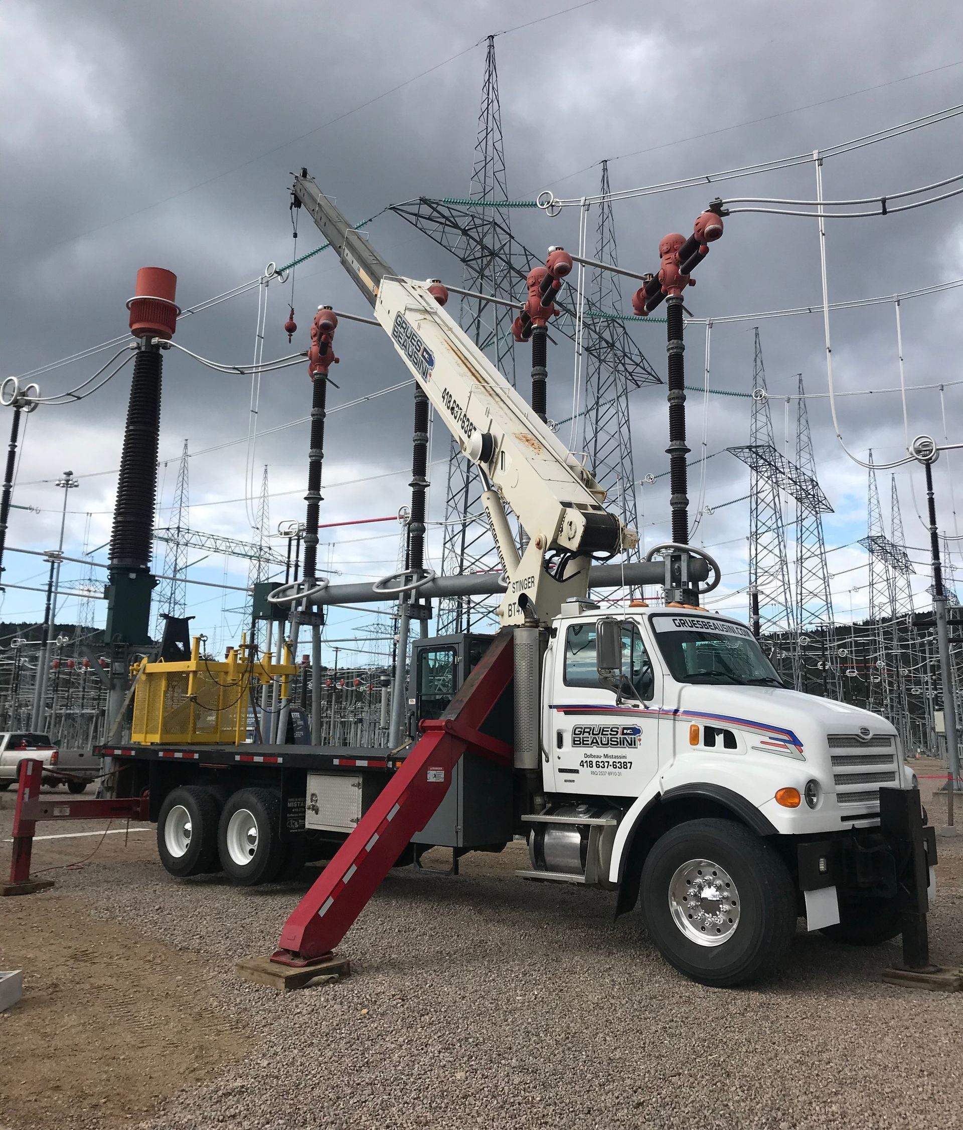 Un camion avec une grue attachée est garé devant une centrale électrique.