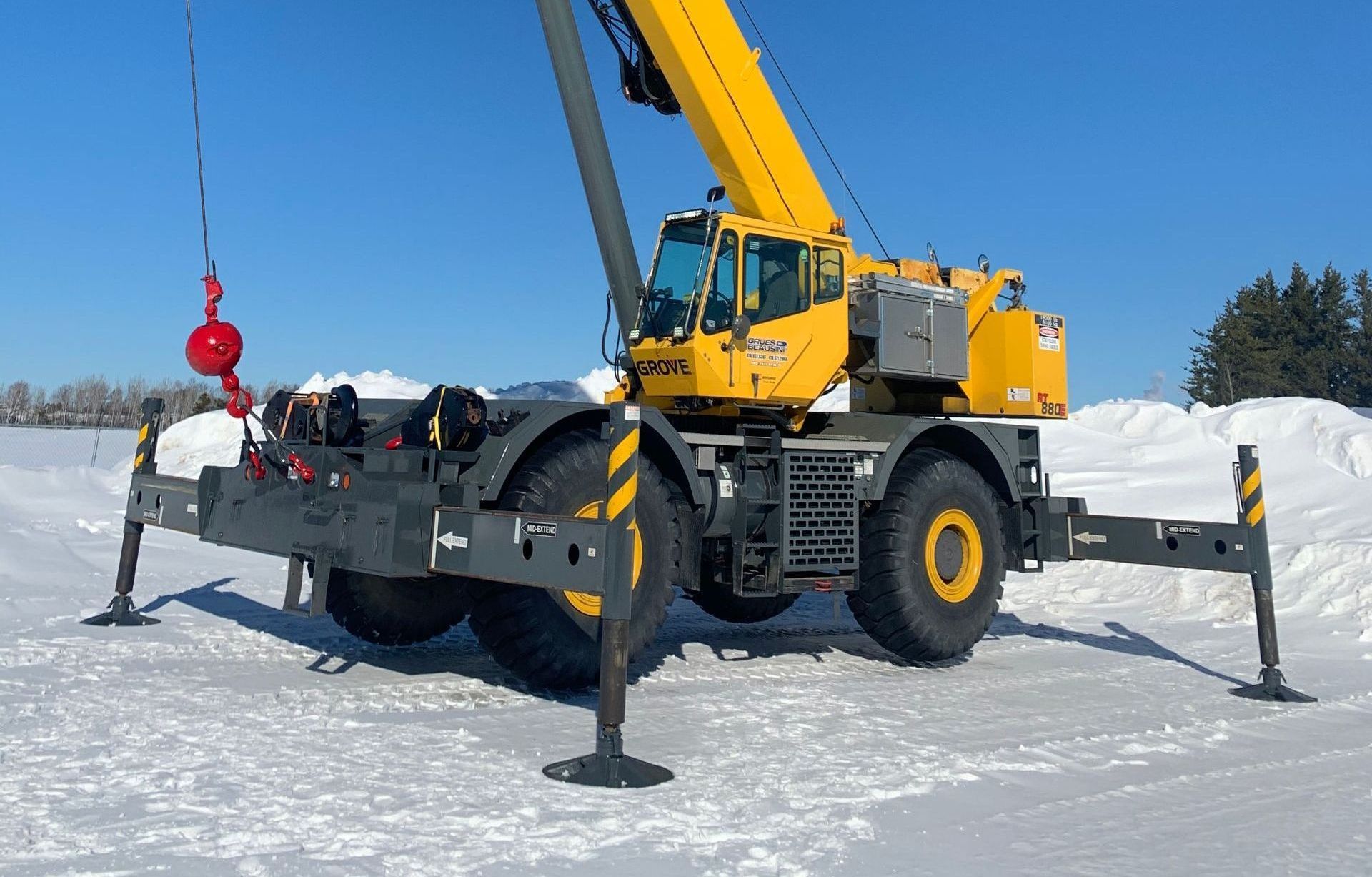 Une grande grue jaune est garée dans la neige.
