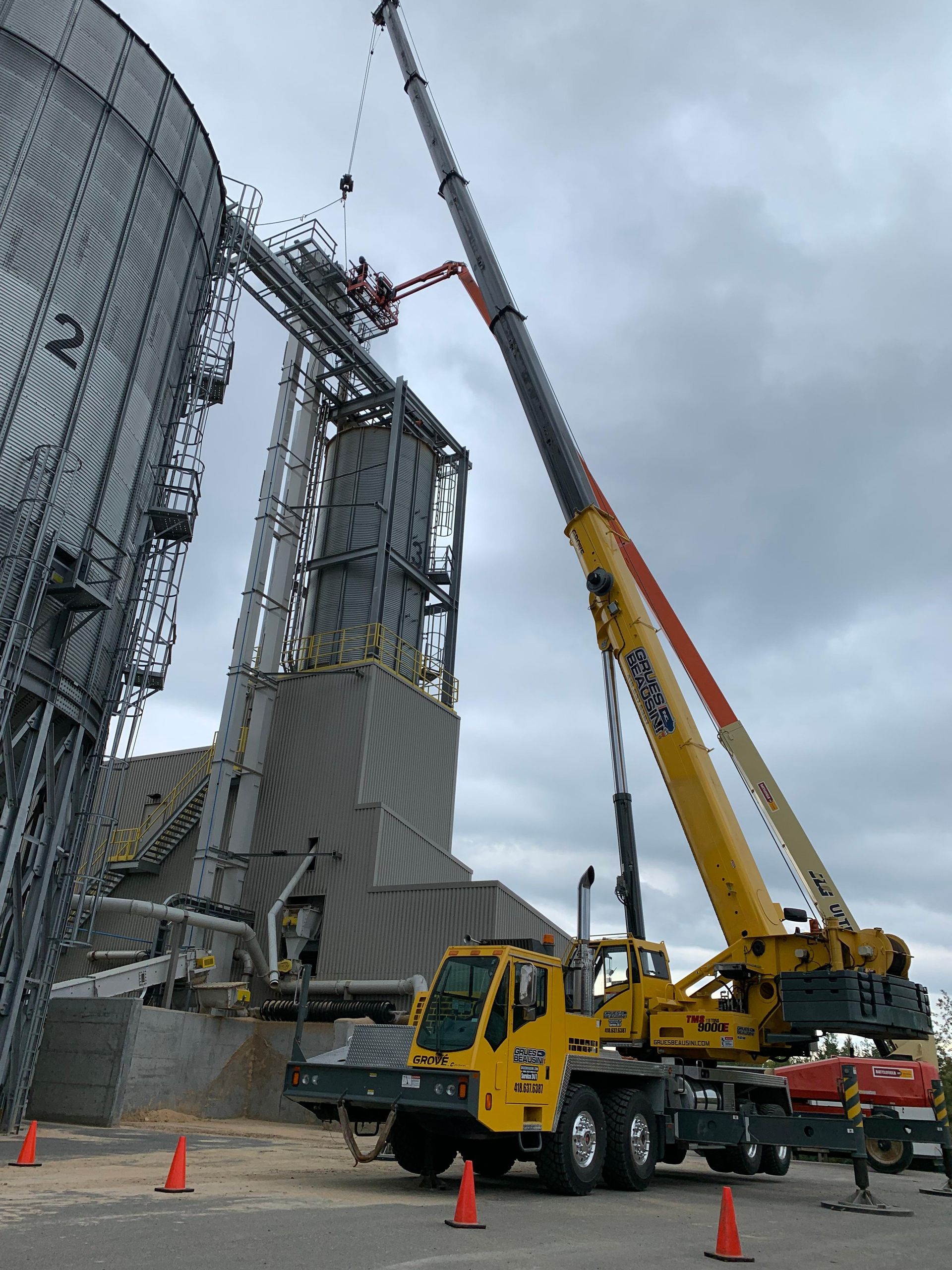 Un gros camion jaune avec une grue attachée dessus