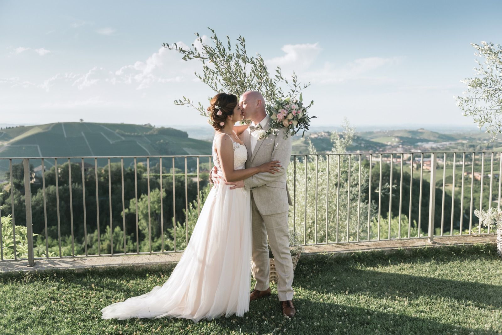 Couple kissing outdoors during their wedding with a scenic background.
