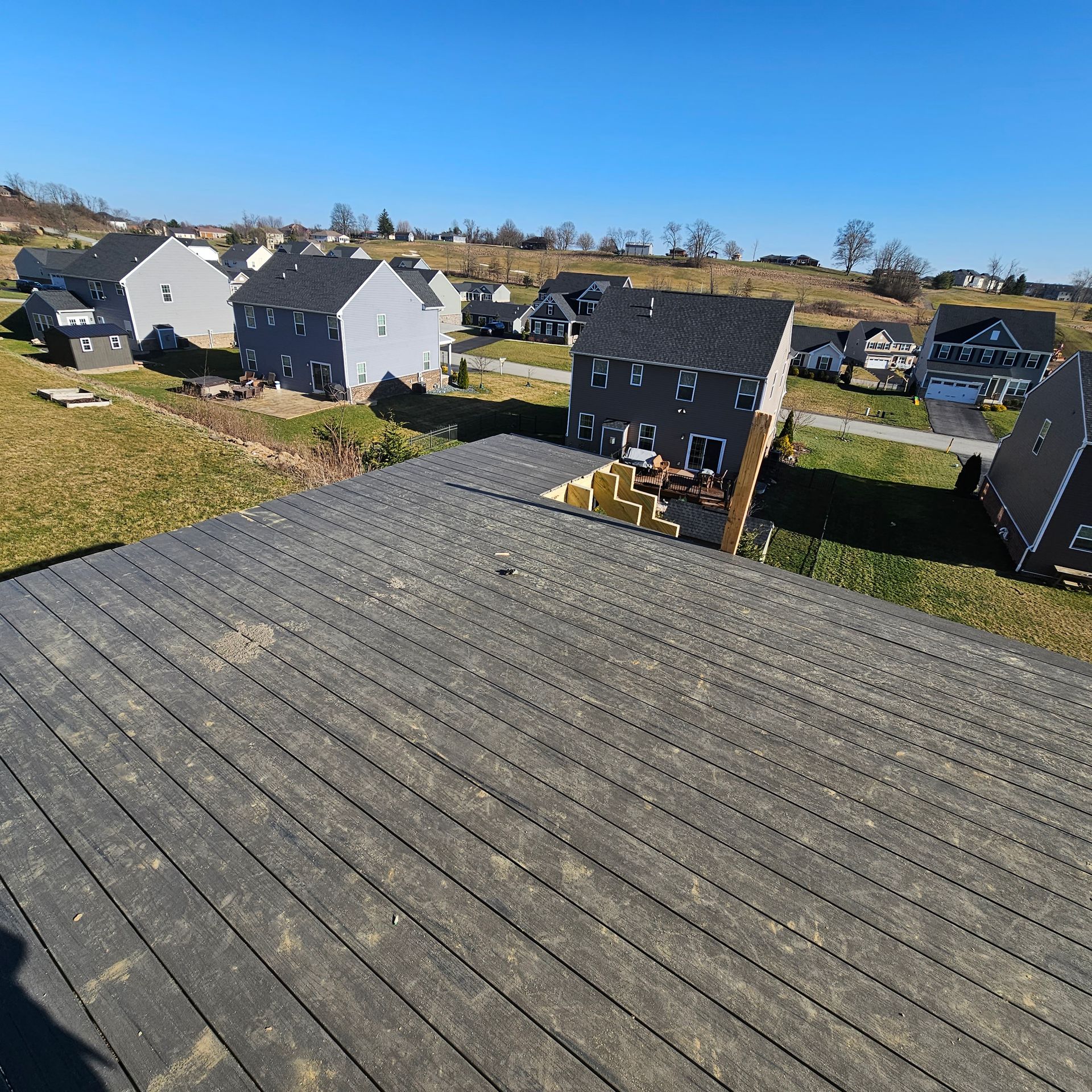Overhead view of rooftops in a suburban neighborhood under a blue sky.