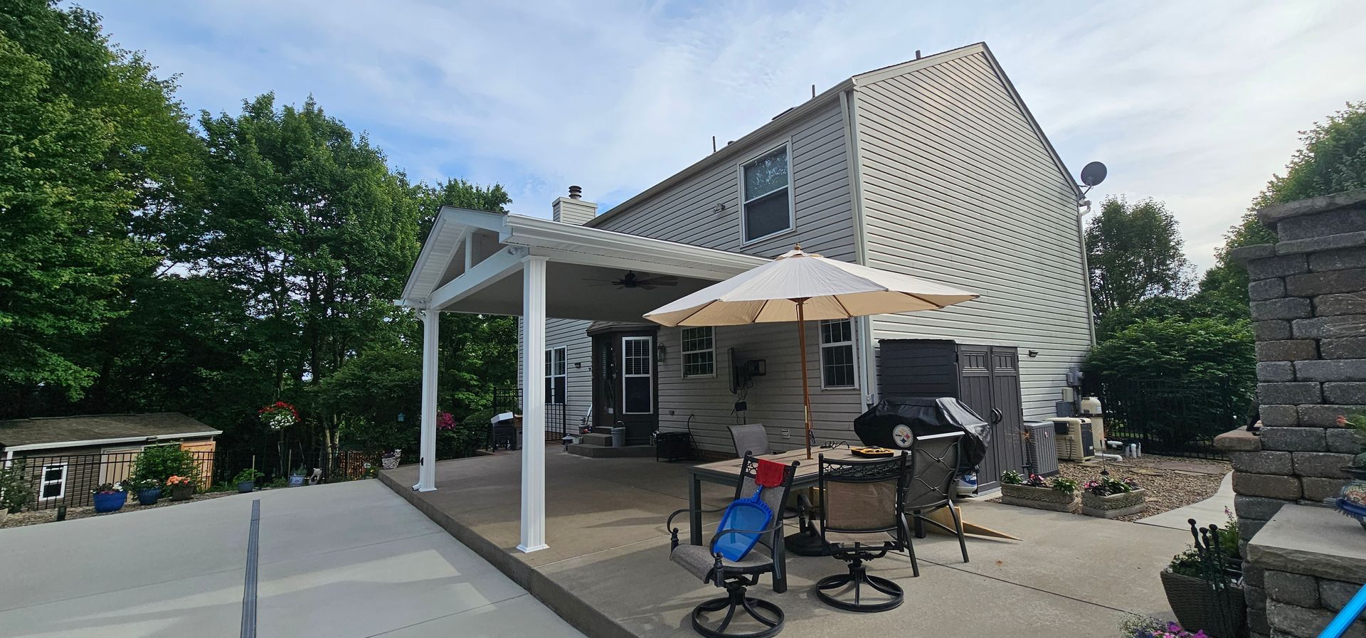 Backyard patio with white pergola, outdoor seating, and house with white siding.