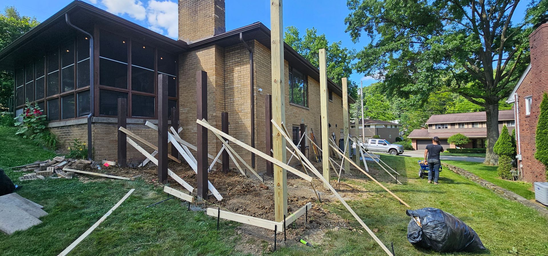 A house with construction underway; fence posts being installed in the yard.