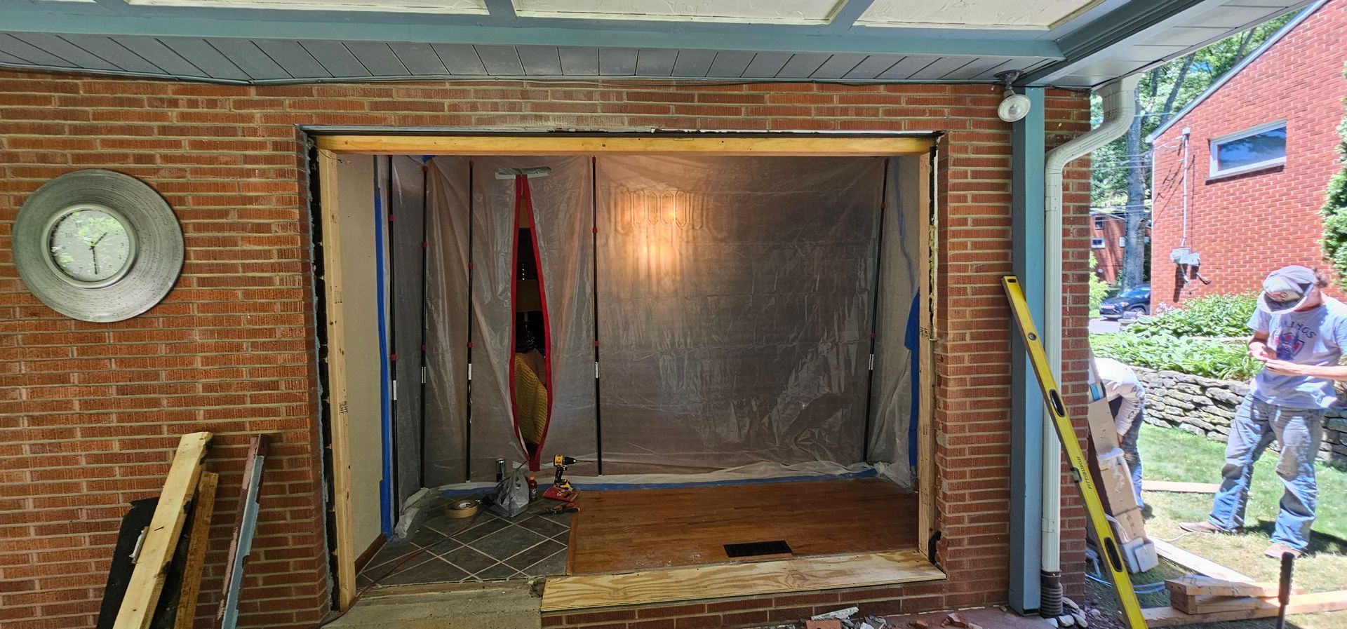 Construction site with brick wall and doorway. A person works outside on the right.