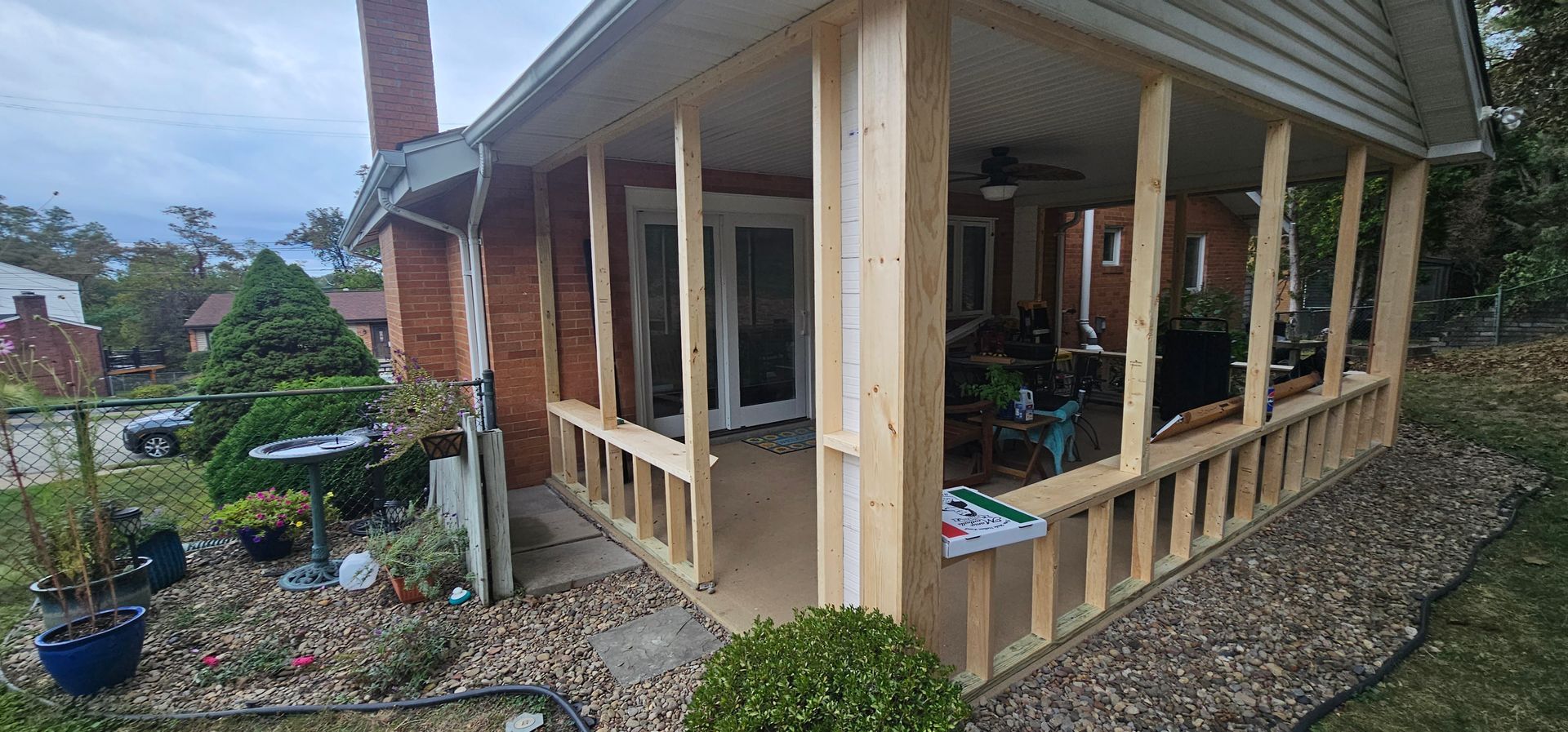A partially built screened porch addition to a brick house with a front yard.