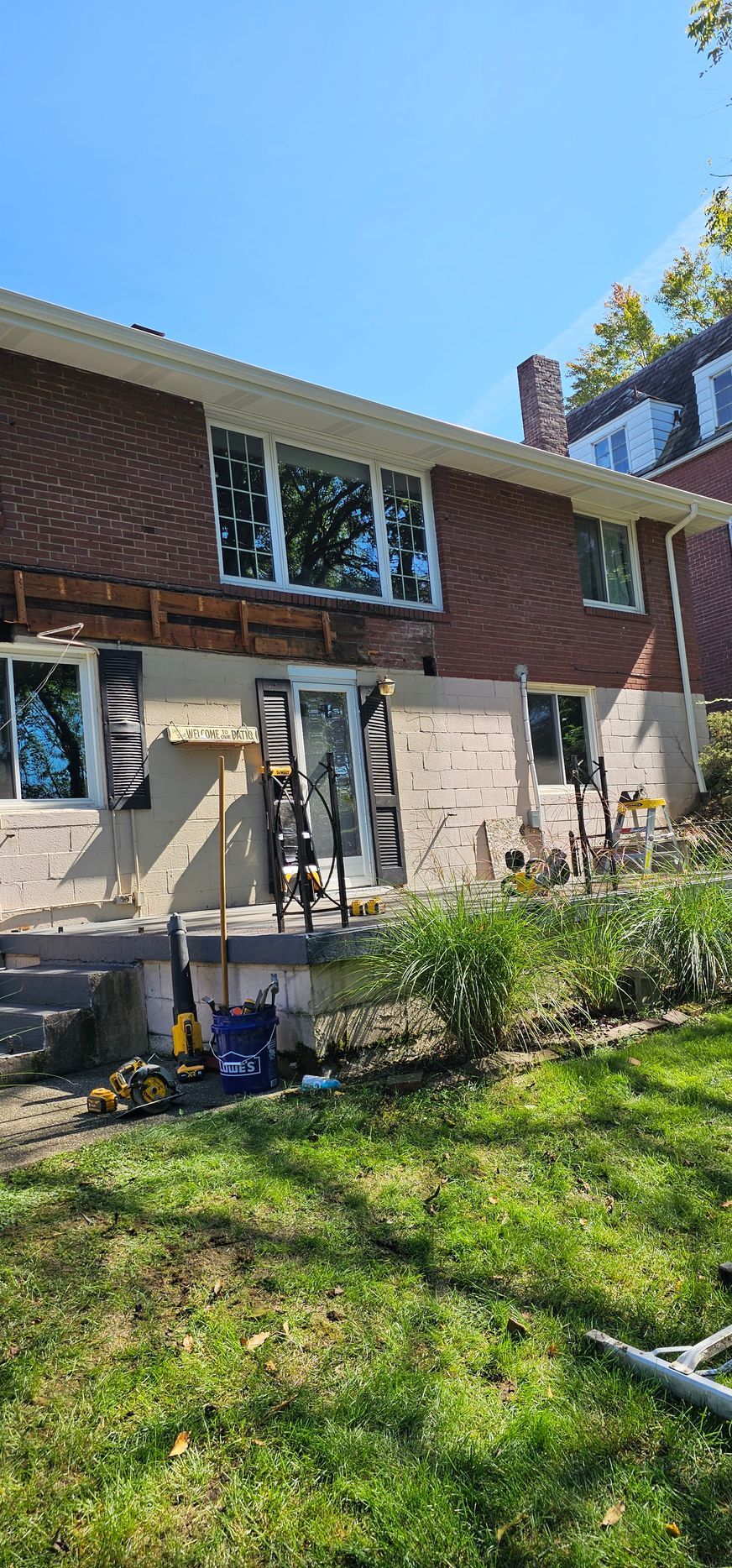 Back of a house under construction; exposed wood, brick, windows, and a lawn.