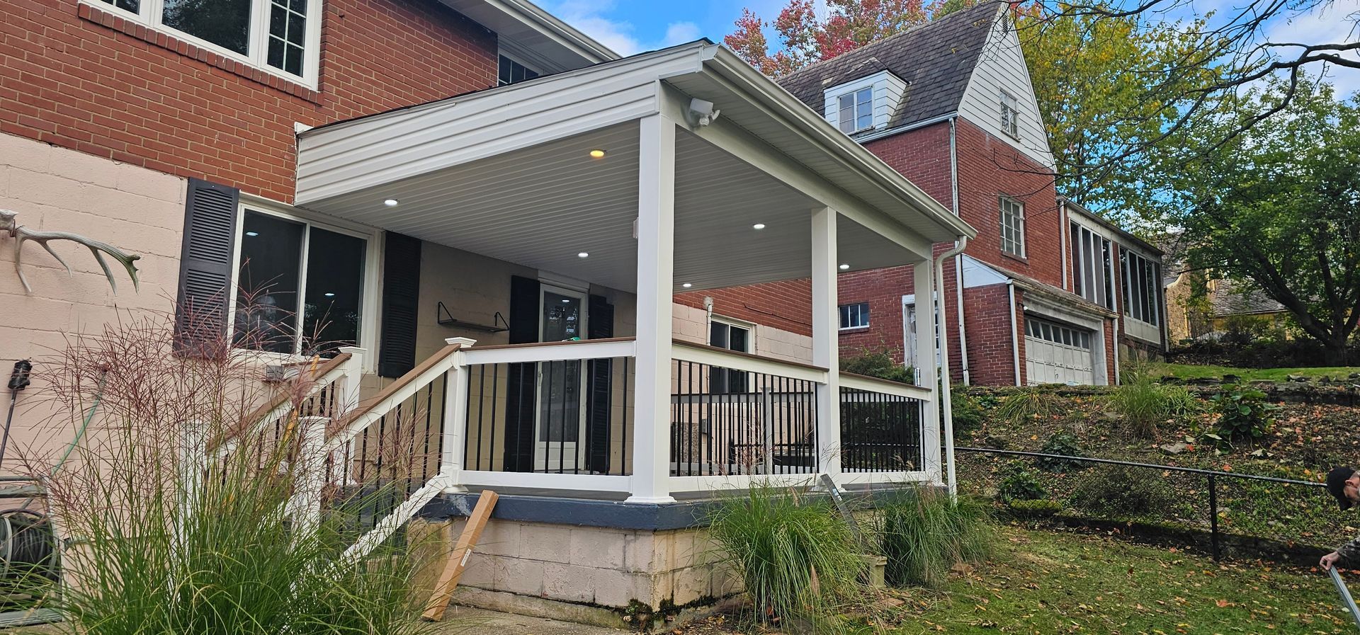 A two-story brick house with a covered porch and a grassy yard.