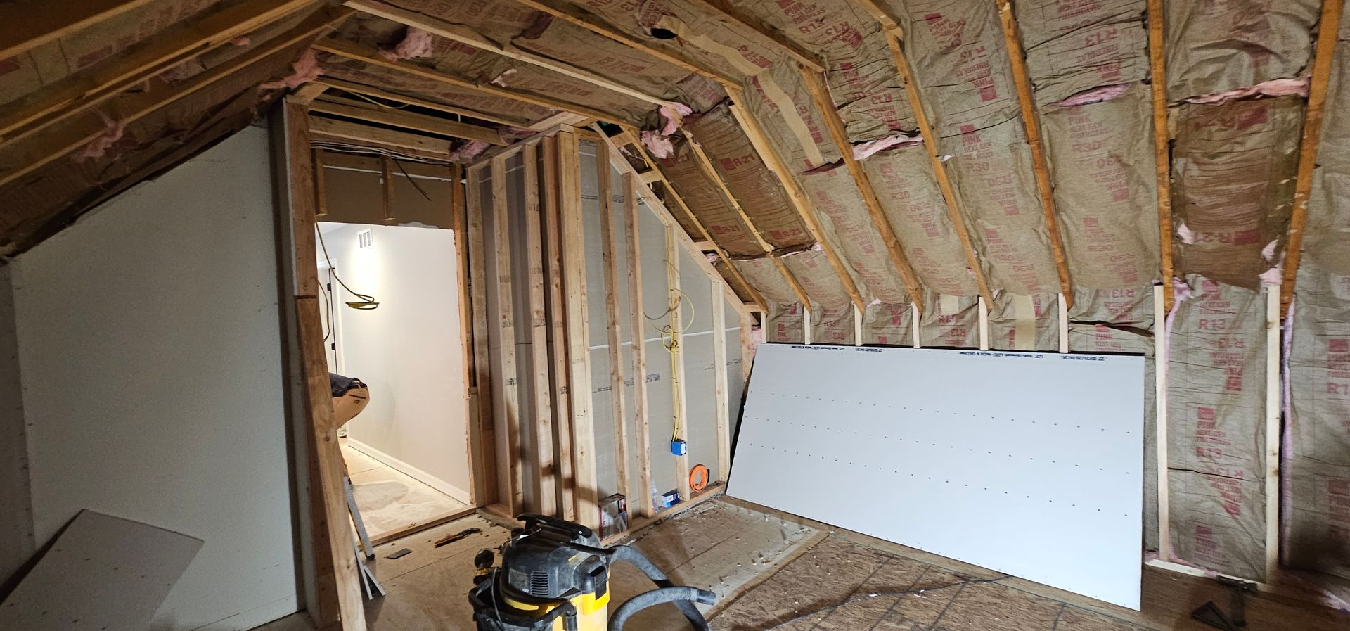 Interior view of a room under construction with exposed wooden framework and insulation.