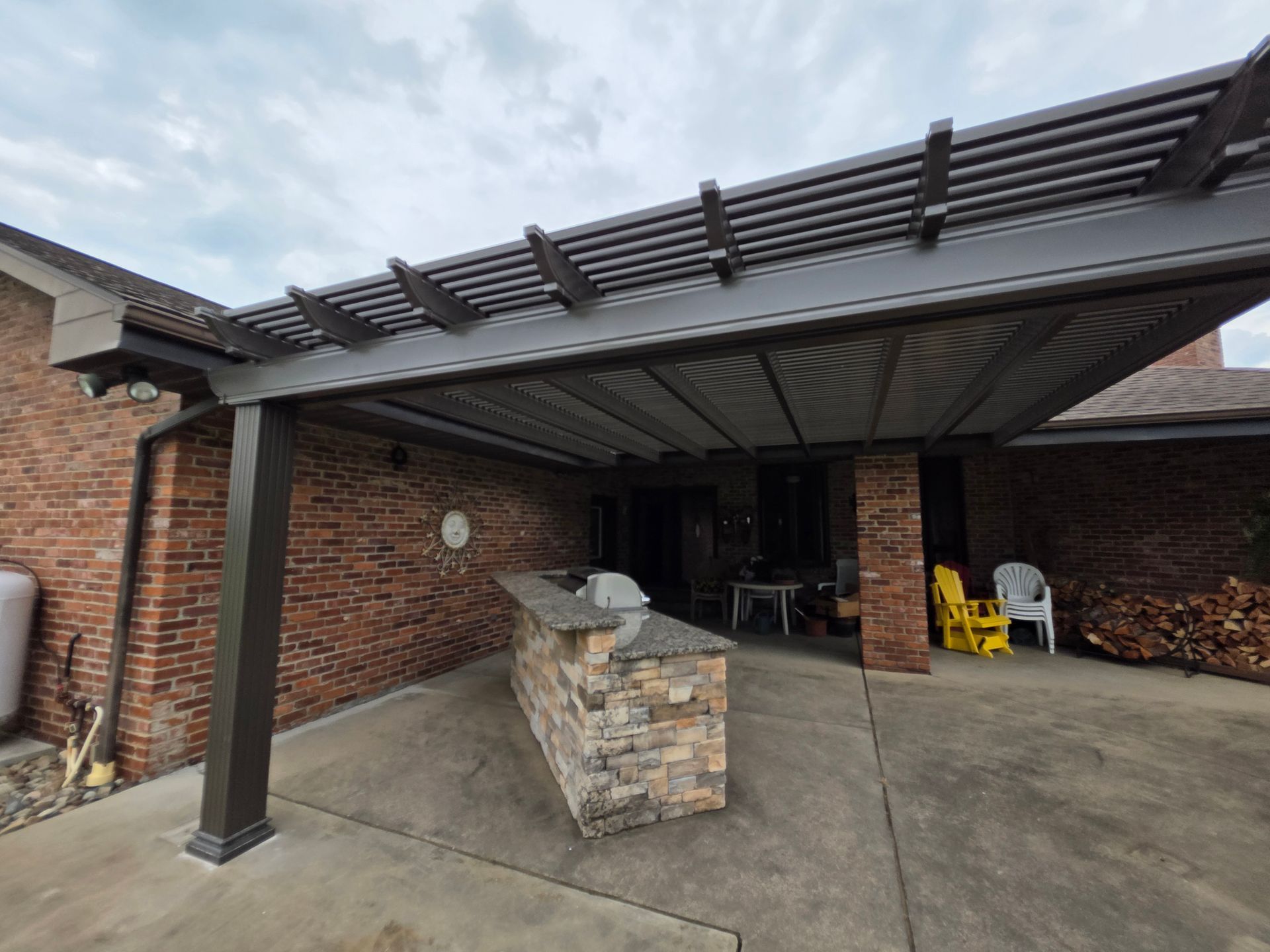 Outdoor patio with pergola and brick accents, featuring an outdoor kitchen and seating.