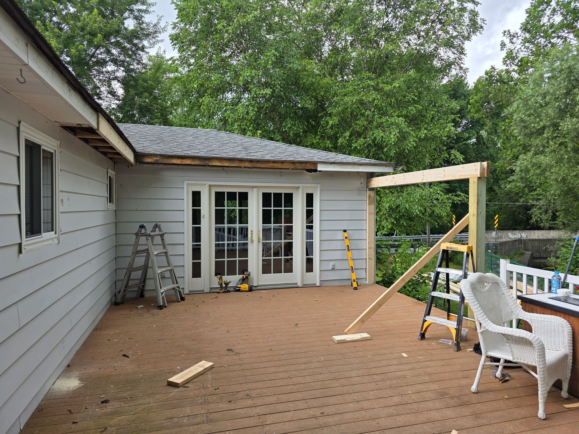 Deck construction with framing next to French doors of a house.
