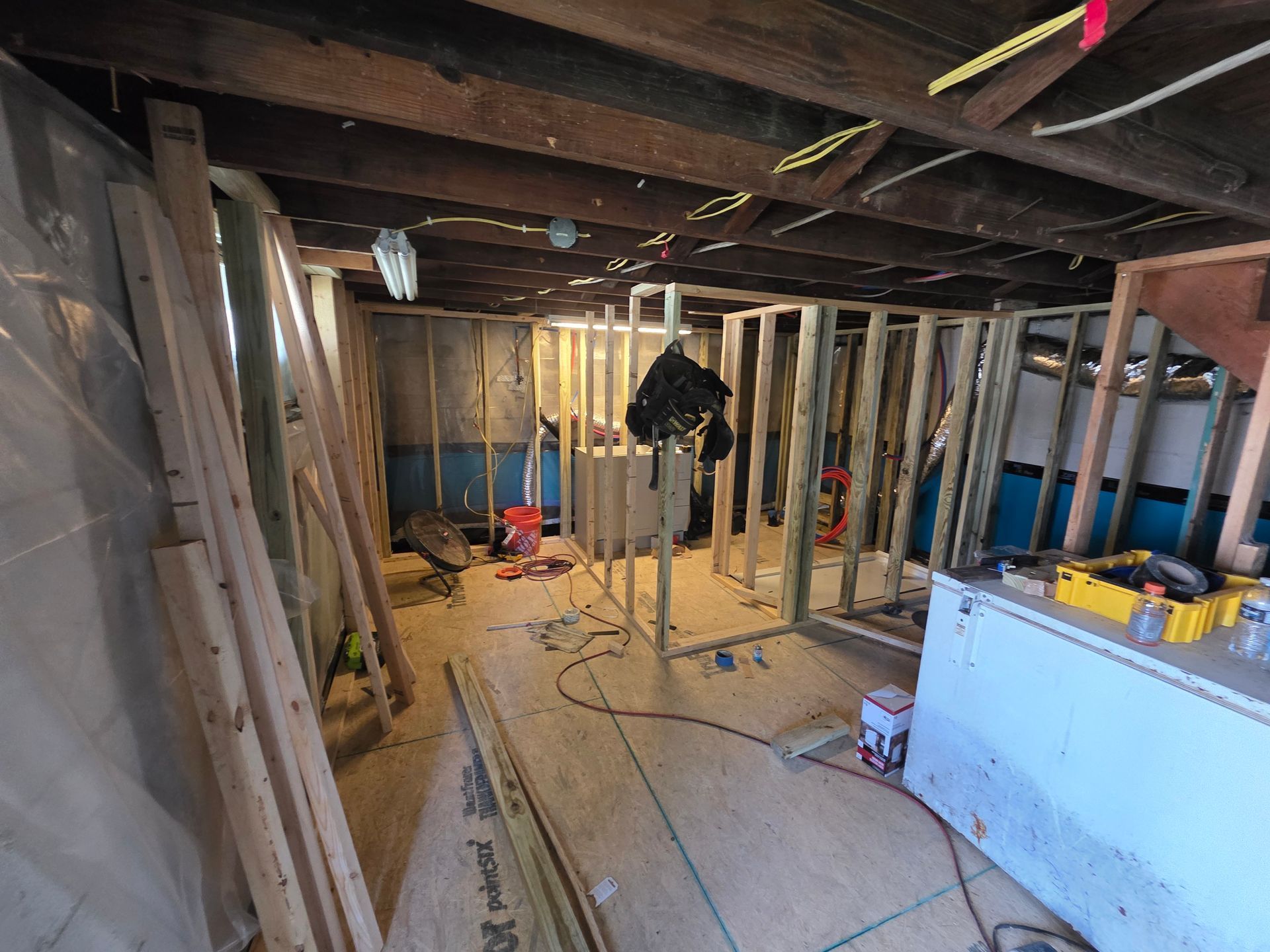 Basement renovation in progress; wooden framing, tools, and materials scattered.