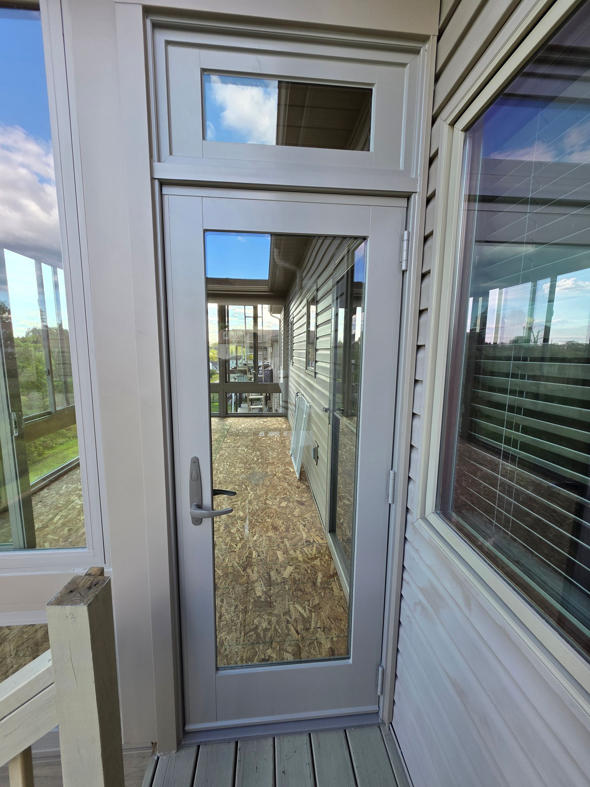 Exterior door with window and sidelights, reflecting a deck and screened porch.