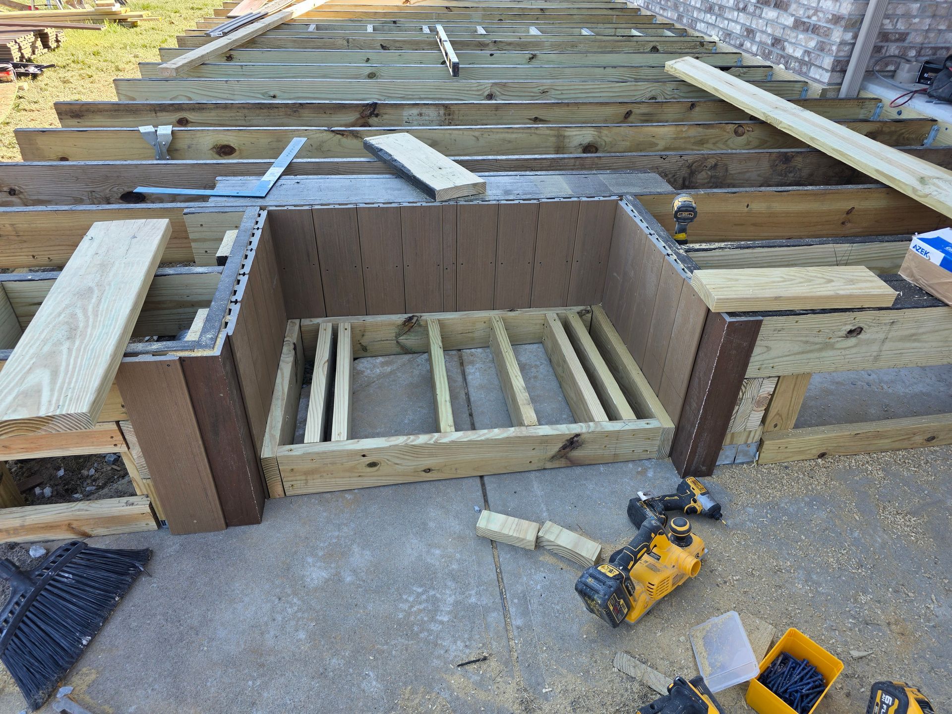 Construction of a deck with a built-in wooden structure; tools and lumber are present.