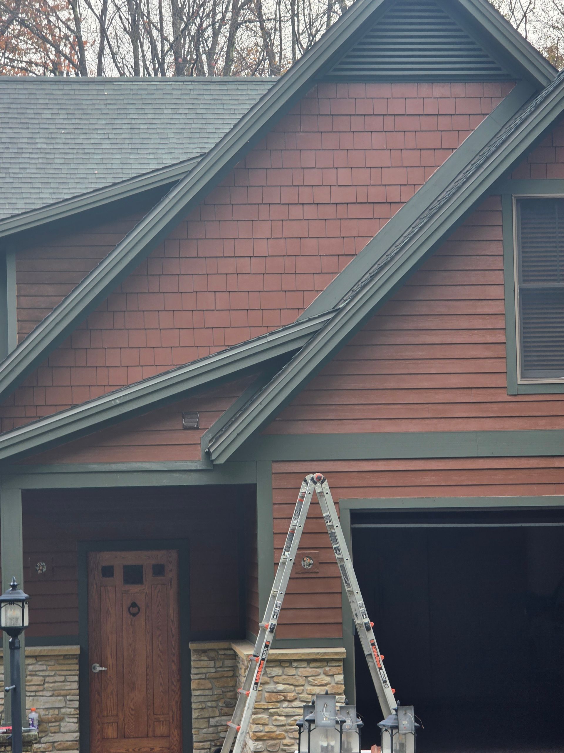 House exterior with red siding, green trim, garage, and a ladder.