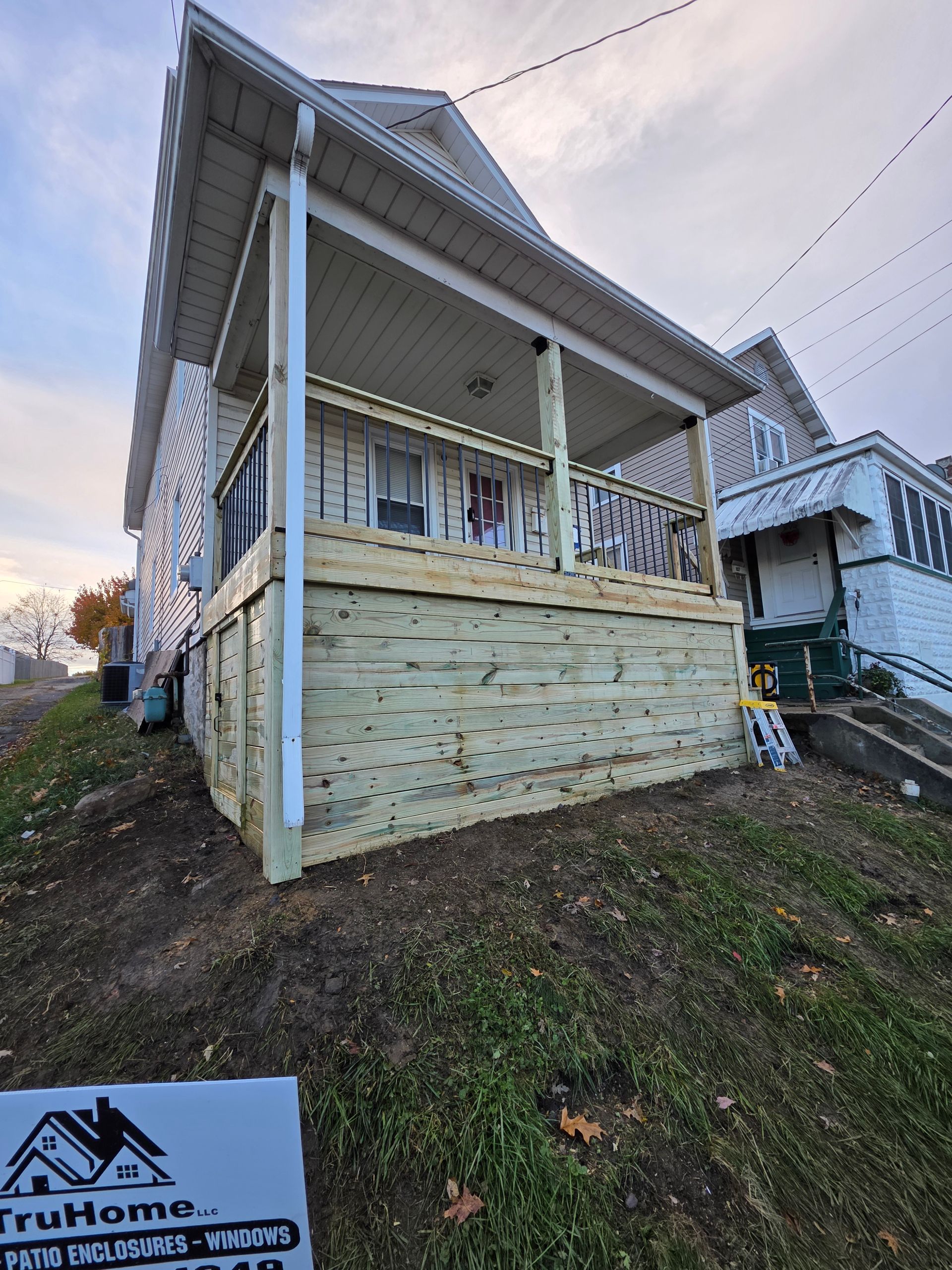 Newly constructed porch with wooden deck and white trim on a house.