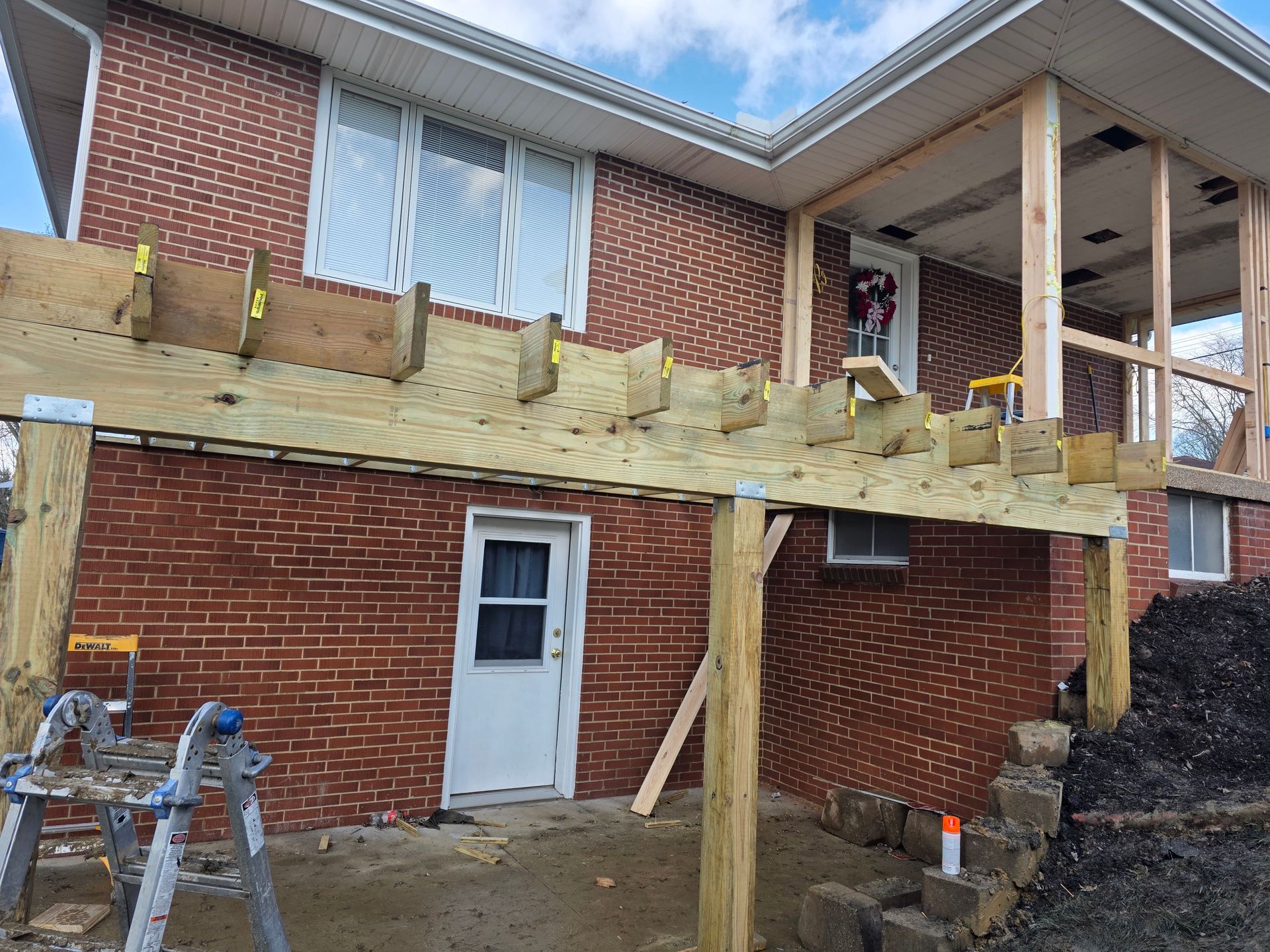A two-story brick house with a partially constructed wooden deck.