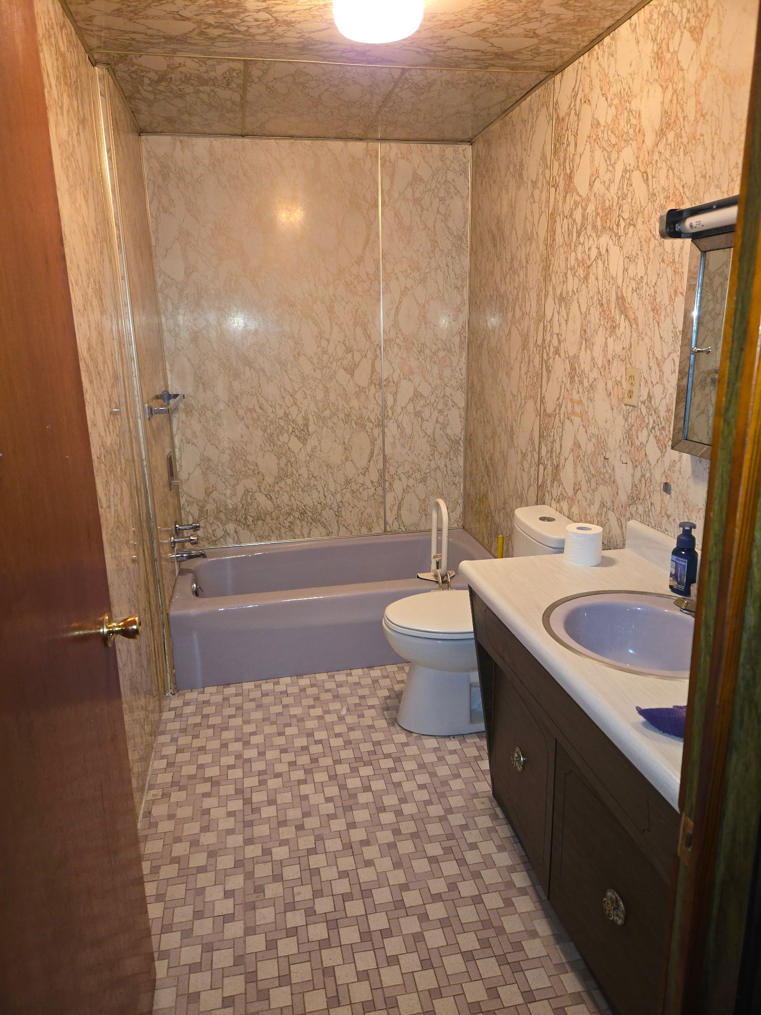 Bathroom with purple bathtub, toilet, and sink; patterned walls and floor.