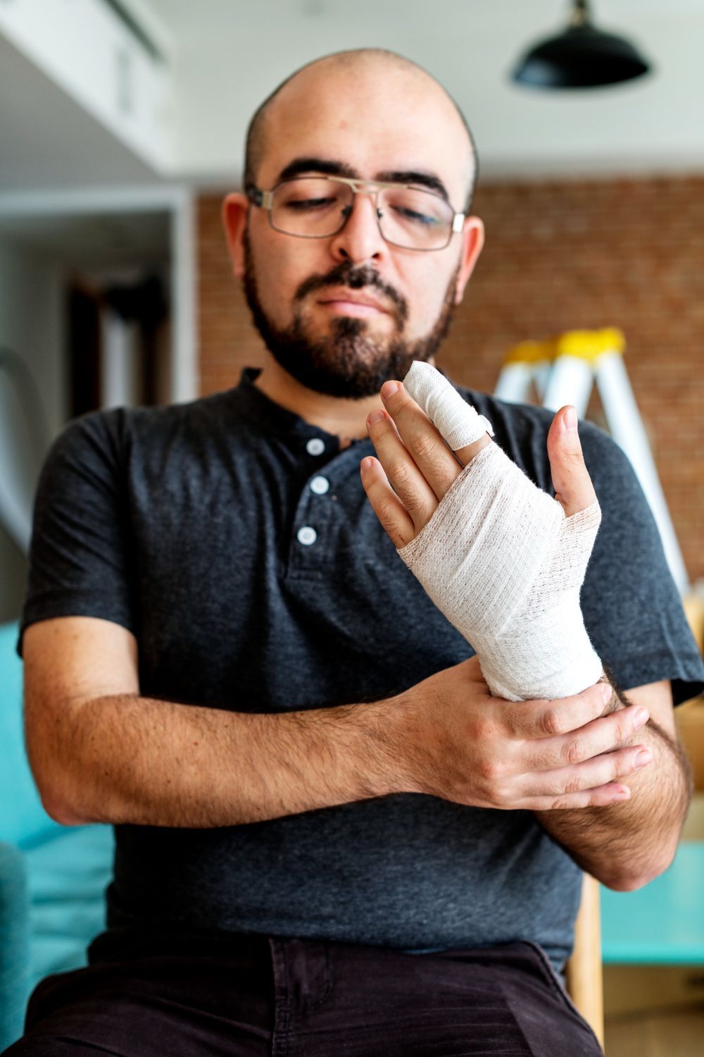 Person with a bandaged hand examining their wrist in a home setting