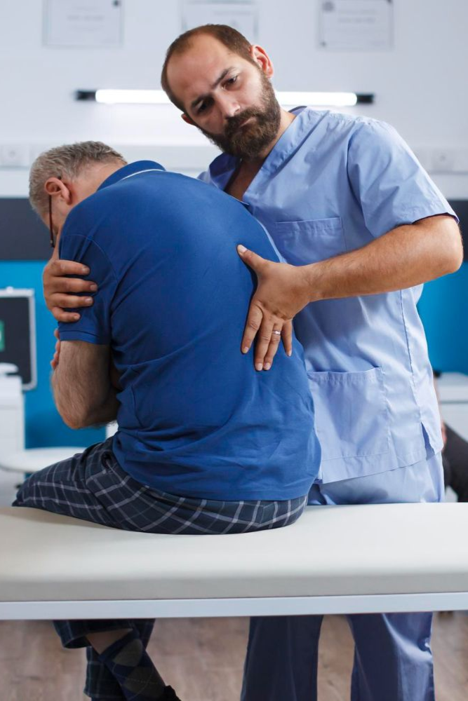 Doctor examining a patient’s back in a clinic room