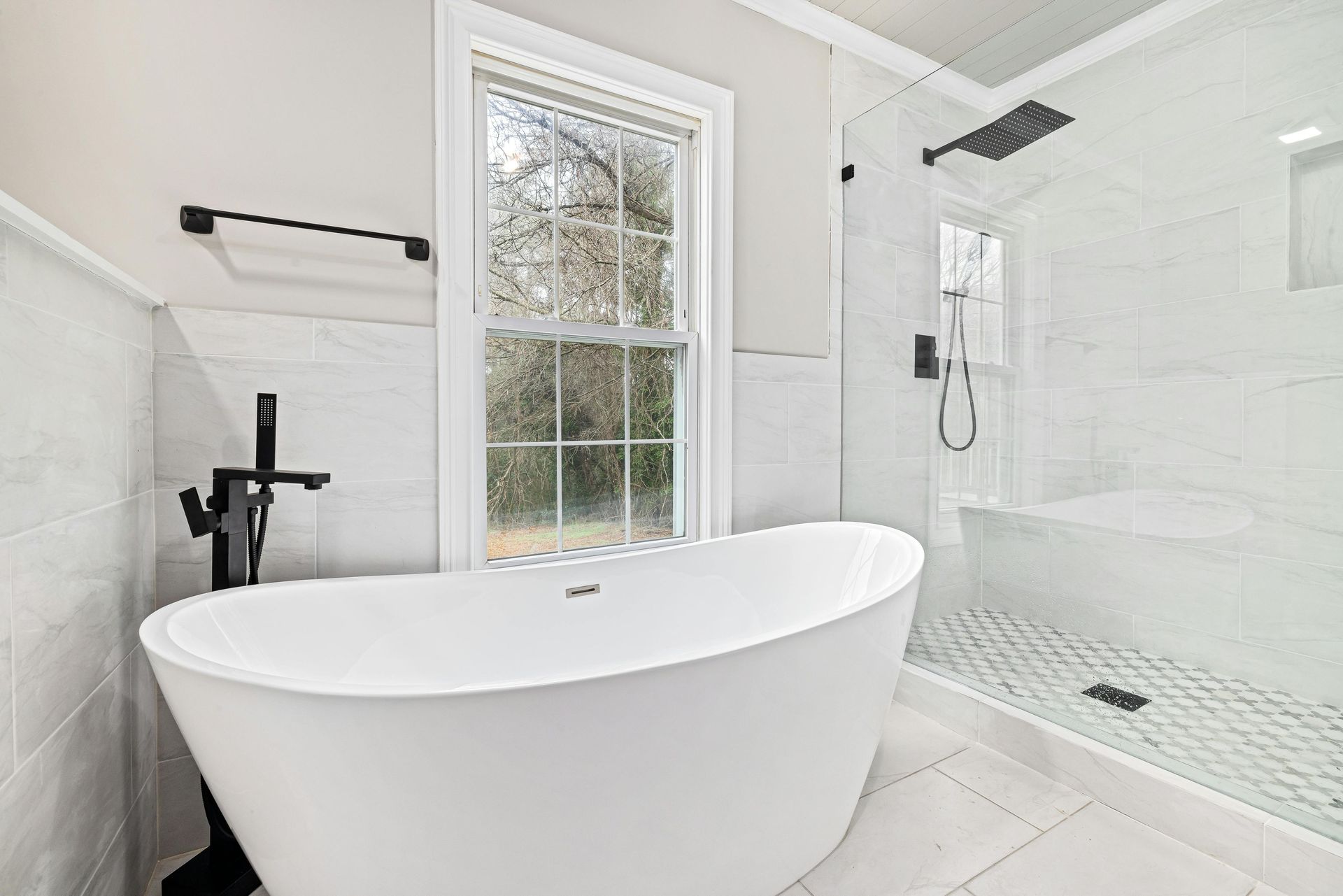 Bright modern bathroom with freestanding tub, walk-in shower, and window