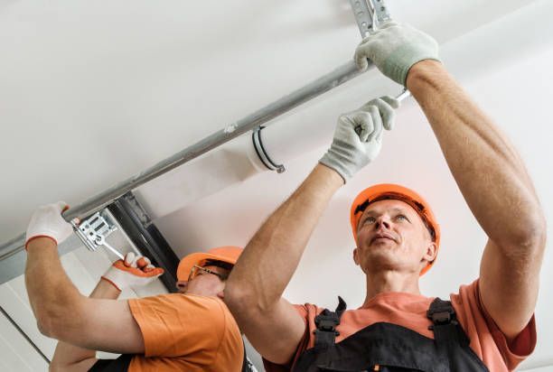 Two men are working on a garage door.