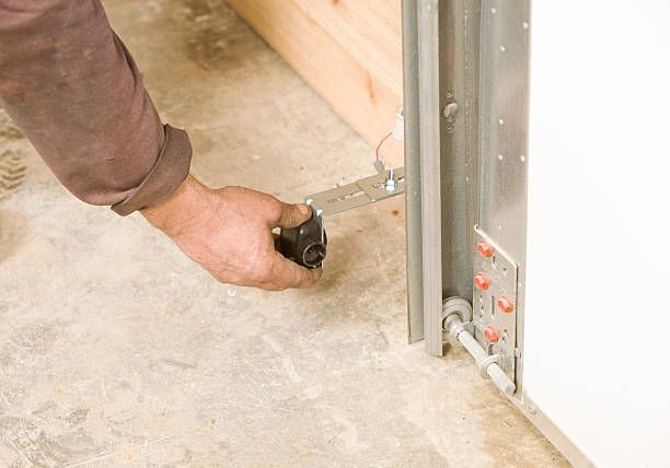 A person is fixing a garage door with a wrench.