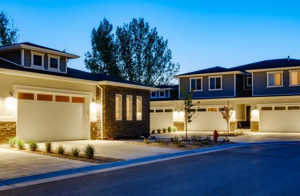 A row of houses with garages are lit up at night.