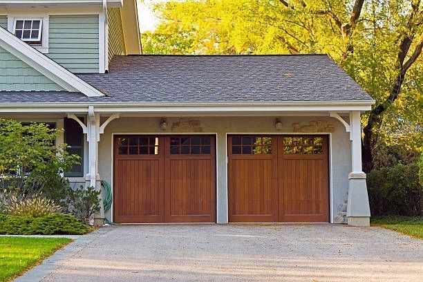 A house with two wooden garage doors and a driveway.