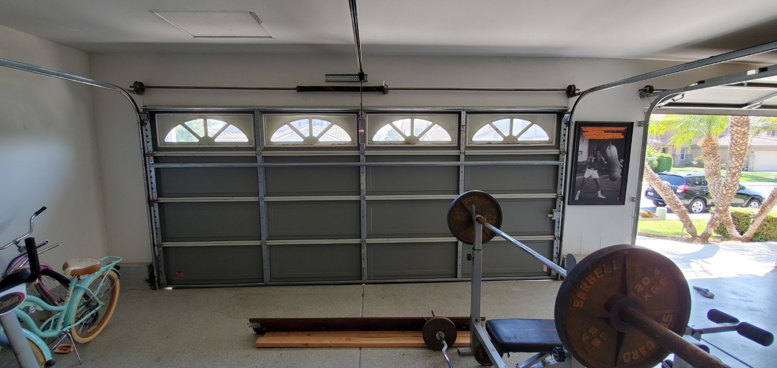 A garage with a bicycle and a barbell in it.