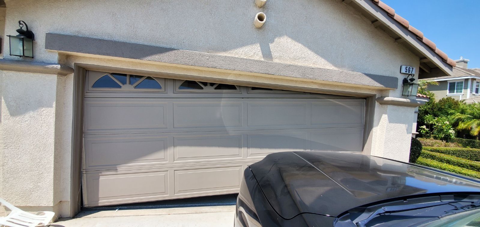 A car is parked in front of a garage door that is open.