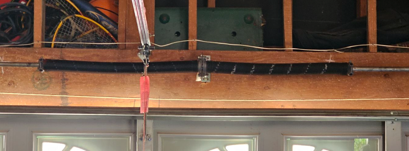 A close up of a garage door spring hanging from the ceiling.