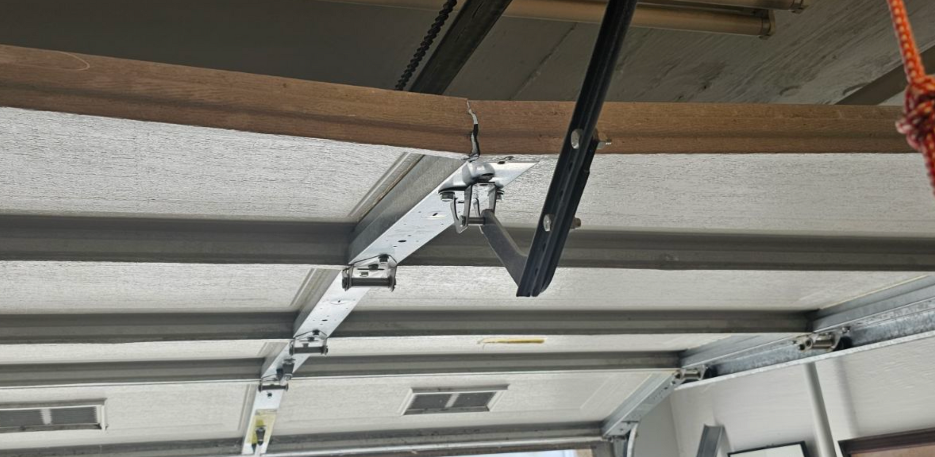 A garage door opener is hanging from the ceiling of a garage.