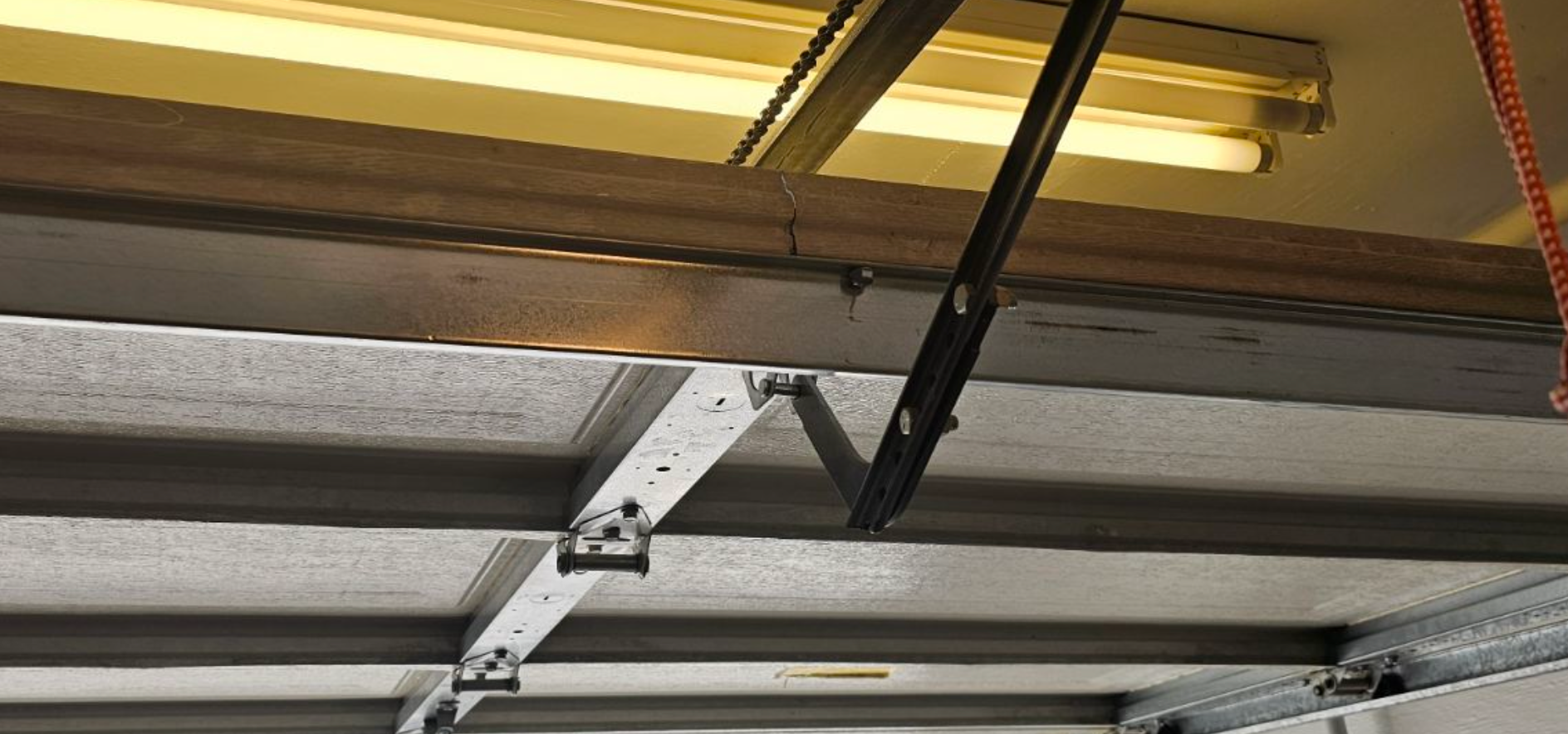 A garage door opener is hanging from the ceiling of a garage.