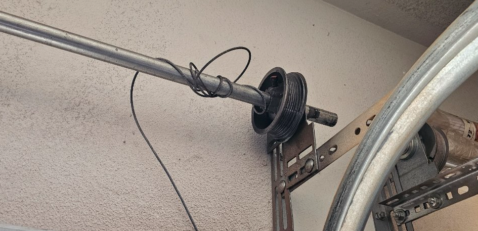 A close up of a garage door opener with a wire hanging from it.