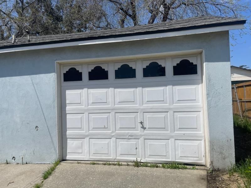 A blue garage with a white garage door and a roof.