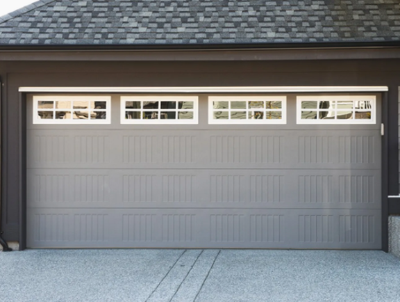 A gray garage door with white windows and a black roof