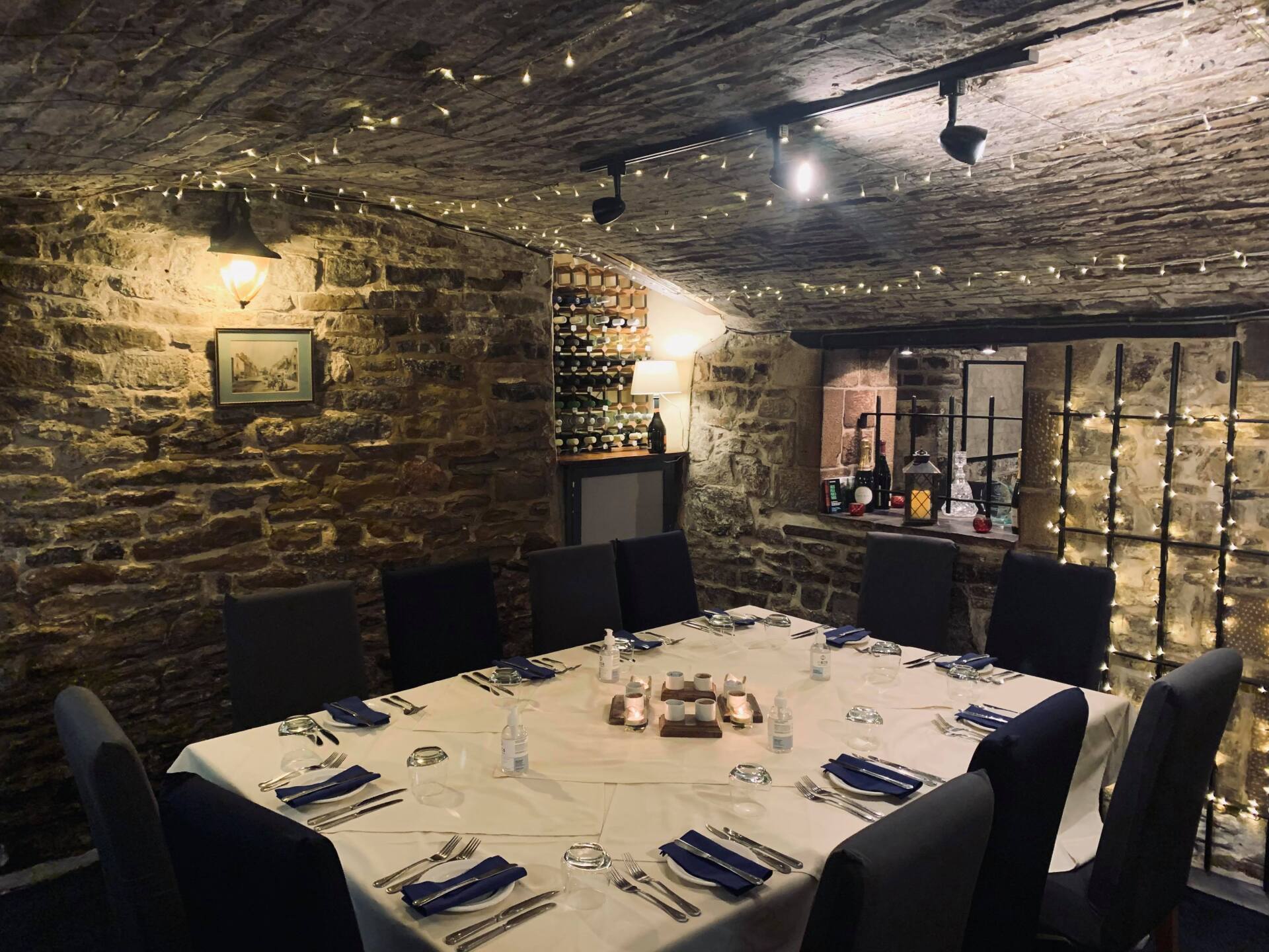 A dining room with a long table and chairs and a brick wall.