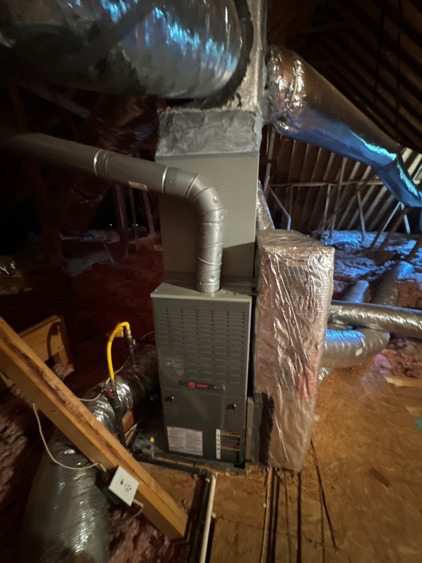 A furnace is sitting in the attic of a house.