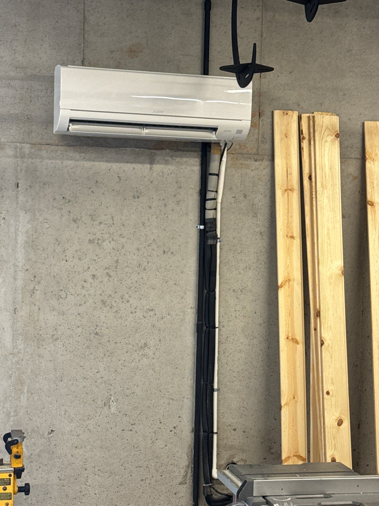 A white air conditioner is mounted to a concrete wall