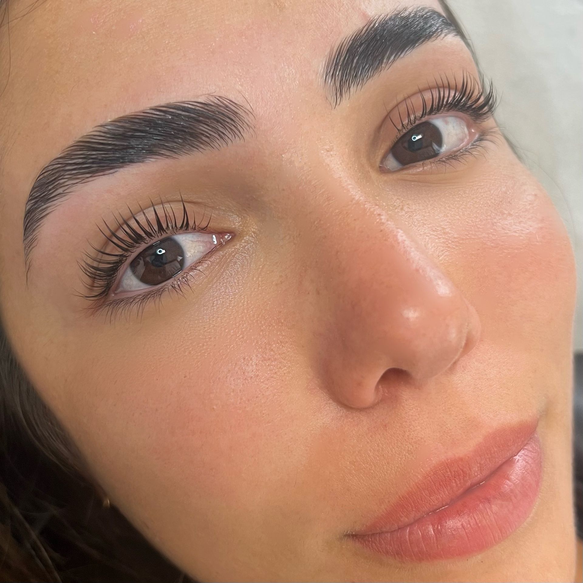 A Woman's Face With Freshly Shaped, Dark Eyebrows, Long Eyelashes, and Glossy Lips — Isola Beauty in Corrimal, NSW