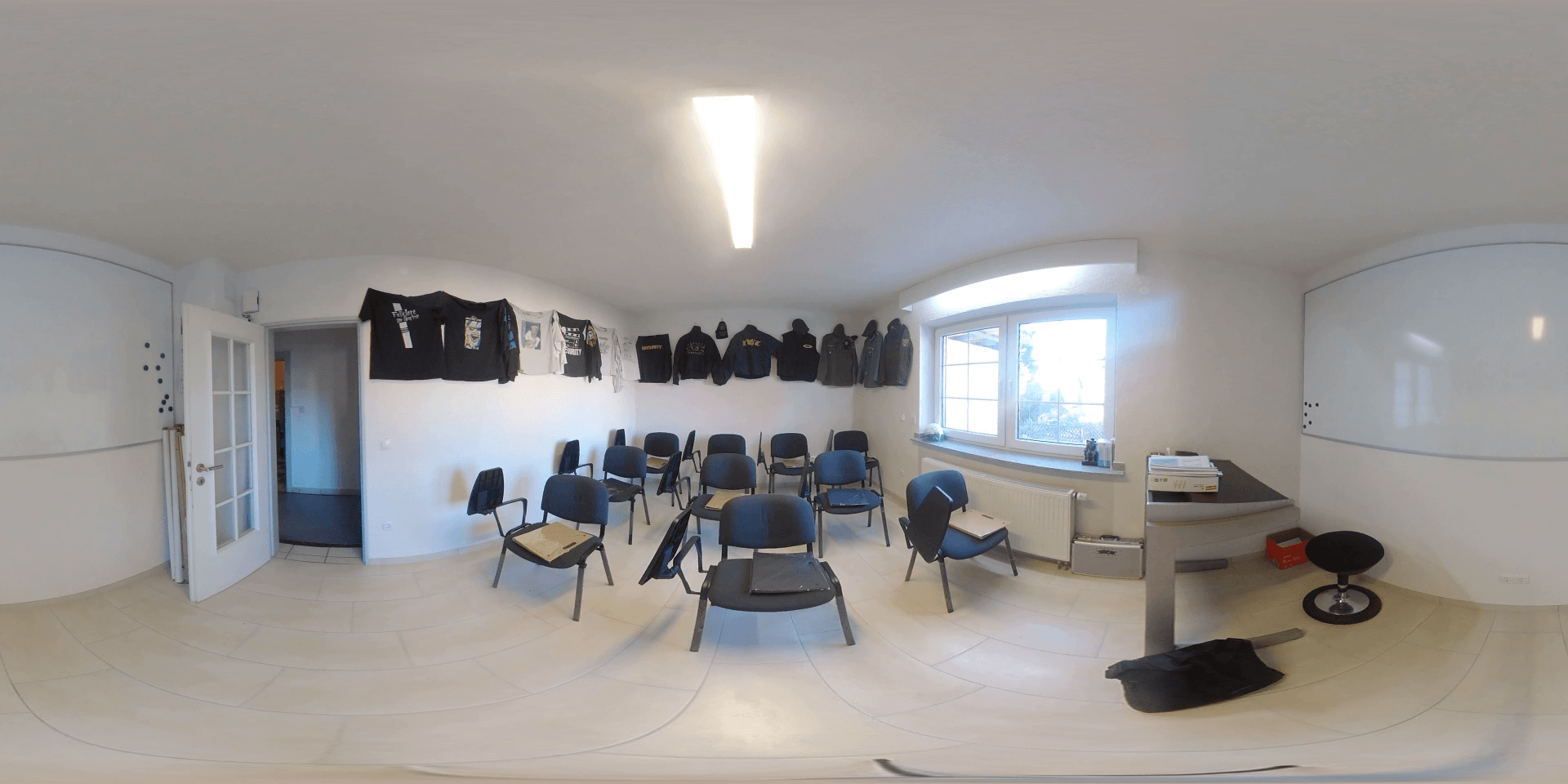 Ein leeres Klassenzimmer mit Stühlen, einem Tisch, einem Fenster und einer Tür.