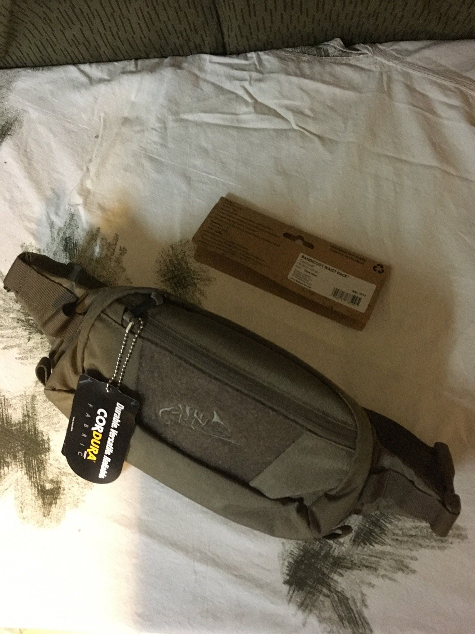 Gürteltasche. Die Gürteltasche ist olivgrün und mit einem Etikett versehen.